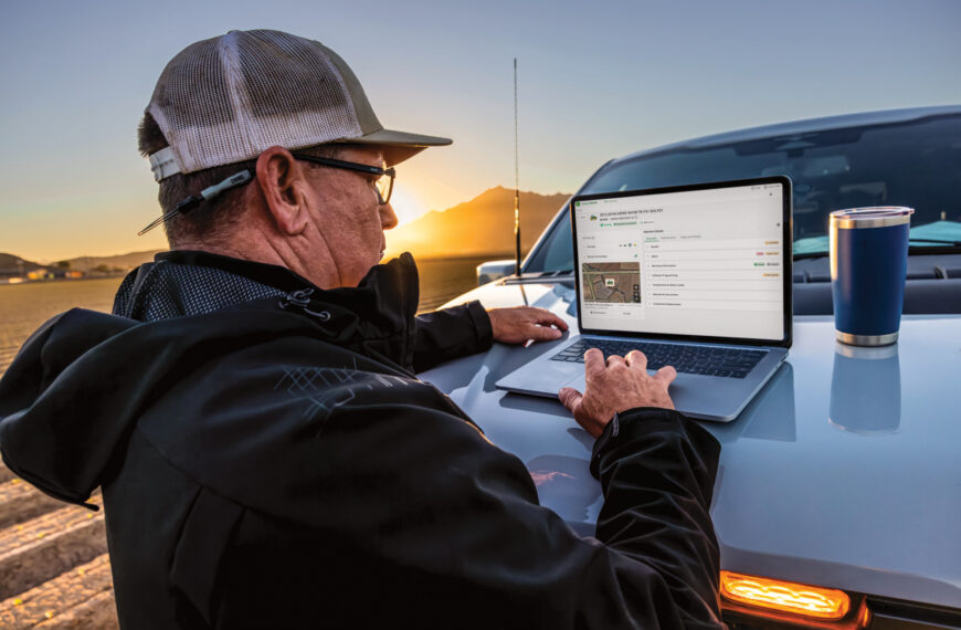 man views information on laptop placed on truck hood.
